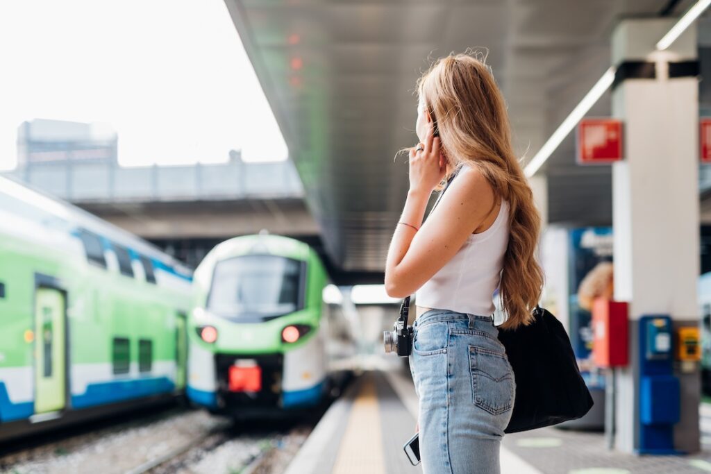 young caucasian woman waiting train at railway